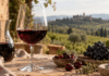 Ein Glas Rotwein neben einer Karaffe, Kirschen und dunklen Trauben.